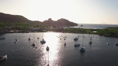 Lipari Adası 'nın deniz kıyısındaki hava manzarası. Yeşil ağaçlar ve binalar. Dağlar ve mavi gökyüzü. Yatlar, katamaranlar ve tekneler. Sicilya, İtalya