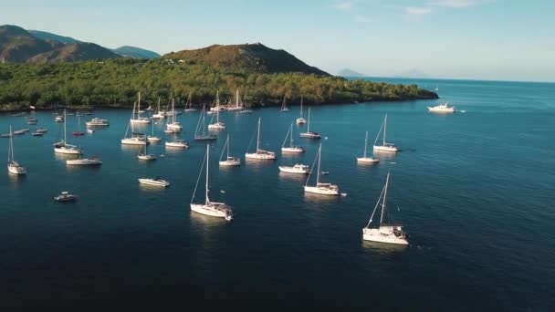 Vista aérea de veleros blancos cerca de las islas Lipari, Sicilia, Italia. Gente caminando por el muelle. Mar Mediterráneo. Montañas y cielo azul — Vídeo de stock