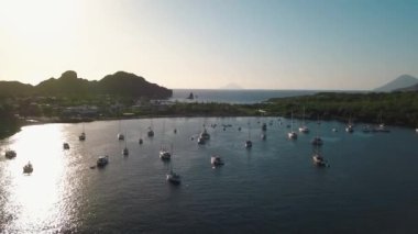 Lipari Adası 'nın deniz kıyısındaki hava manzarası. Yeşil ağaçlar ve binalar. Dağlar ve gün doğumu. Yatlar, katamaranlar ve tekneler. Sicilya, İtalya