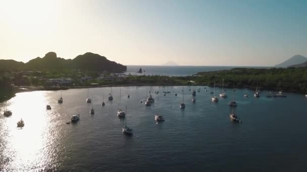 Uitzicht vanuit de lucht op de kust van Lipari Island. Groene bomen en gebouwen. Bergen en zonsopgang. Jachten, catamarans en boten. Sicilië, Italië — Stockvideo