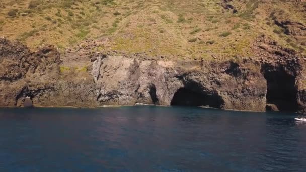 Vista aérea em barco branco ancorado perto da caverna da ilha de Lipari, no mar Mediterrâneo. Algumas pessoas a bordo e alguma natação. Sicília, Itália — Vídeo de Stock