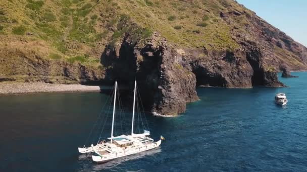 Luftaufnahme auf weißem Katamaran und Ausflugsboot mit Menschen an Bord gegen Felsen der Insel Lipari. Mittelmeer. Sizilien, Italien — Stockvideo