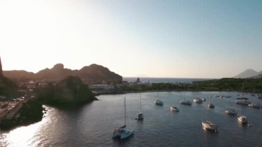 Lipari Adası 'nın deniz kıyısındaki hava manzarası. Yeşil ağaçlar ve binalar. Dağlar ve mavi gökyüzü. Yatlar, katamaranlar ve tekneler. Sicilya, İtalya