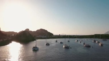 Lipari Adası 'nın deniz kıyısındaki hava manzarası. Yeşil ağaçlar ve binalar. Dağlar ve mavi gökyüzü. Yatlar, katamaranlar ve tekneler. Sicilya, İtalya