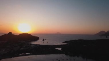 Lipari Adaları 'nda ağaçlar, binalar ve dağlarla hava manzarası. Demir atmış gemiler. Akdeniz, gün batımı. Sicilya, İtalya