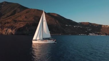 Yelkenlide hava manzarası ve içinde insanlar var. Lipari Adası yakınlarındaki Akdeniz 'de liman ve binalarla demirlemiş. Sicilya, İtalya