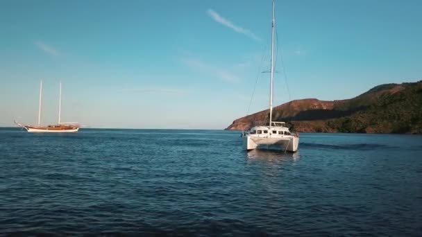 リパリ諸島、シチリア島、イタリアの近くのカタマランとセーリングボートの空中ビュー。地中海だ。山と青空 — ストック動画