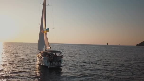 Luftaufnahme auf einem weißen Segelboot mit Menschen, die Spaß an Bord haben. Verankert im Mittelmeer. Lipari Inseln. Sizilien, Italien. Sonnenuntergang — Stockvideo