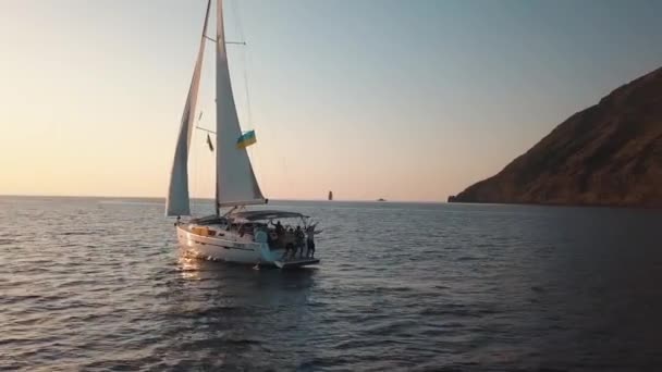 Luchtfoto op zeilboot met mensen aan boord. Verankerd in de Middellandse Zee in de buurt van Lipari Island met jachthaven en gebouwen erop. Sicilië, Italië — Stockvideo