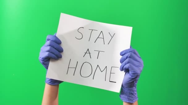 Hände Ärztin in blauen Handschuhen mit einem Schild mit der Aufforderung, zu Hause zu bleiben. Grüner Bildschirm. Nahaufnahme — Stockvideo