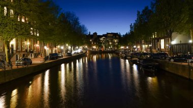 Amsterdam 'da bir kanal boyunca binaların gece manzarası.