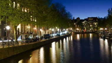 Amsterdam 'da bir kanal boyunca binaların gece manzarası.