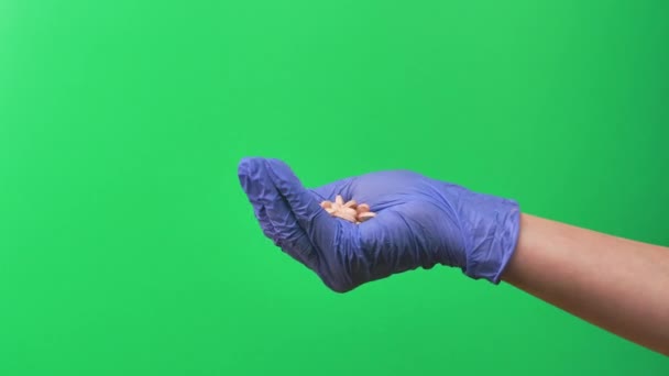 Doctor shows a lot pills at her palm against green screen. Doctors woman hand in blue protective glove closeup. — Stock Video
