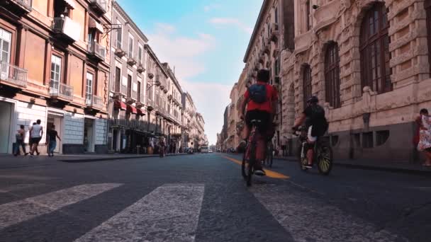 CATANIA, SICILIA, ITALIA - SEPTIEMBRE, 2019: Ciclistas a lo largo de la calle, centro histórico. Movimiento lento — Vídeos de Stock