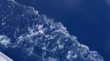 Mavi deniz yüzeyinde köpüklü dalgalar oluşturan beyaz tekne hızlanıyor.