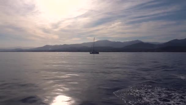 Yacht moving by Mediterranean sea. Cityscape and mountains in distance — Stock Video