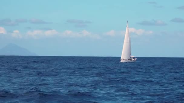 Voilier blanc naviguant en mer contre ciel bleu et montagnes 
