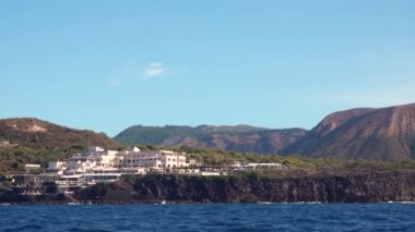 Büyük beyaz otel kompleksi olan dik kayalık dağların manzarası