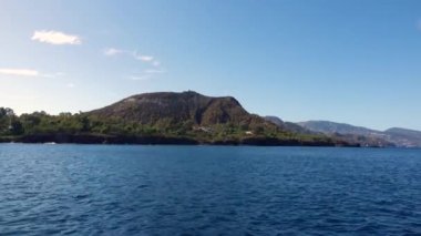 Dağlarda, denizde ve mavi gökyüzünde hareket eden tekneden görüntü