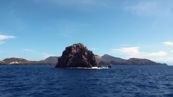 Vågor kraschar på sten i havet mot berg, blå himmel — Stockvideo