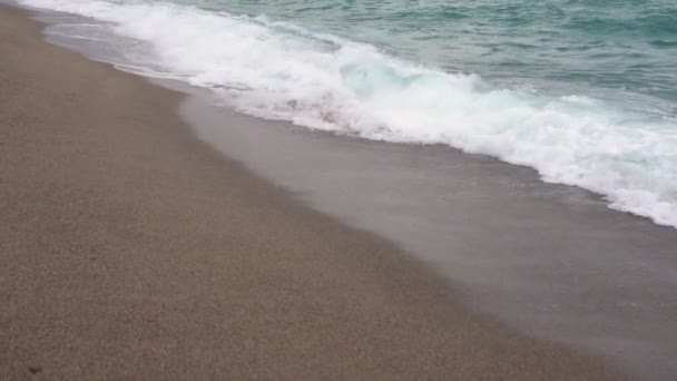 Costura arenosa bañada por olas transparentes con espuma blanca. Movimiento lento — Vídeo de stock