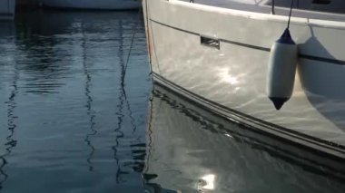 Limana demirlemiş beyaz yelkenli yatta şişme çamurluk.