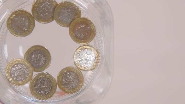ガラス瓶にいくつかのポンドのコインをドロップ誰かのスローモーションワームの目のビュー — ストック動画