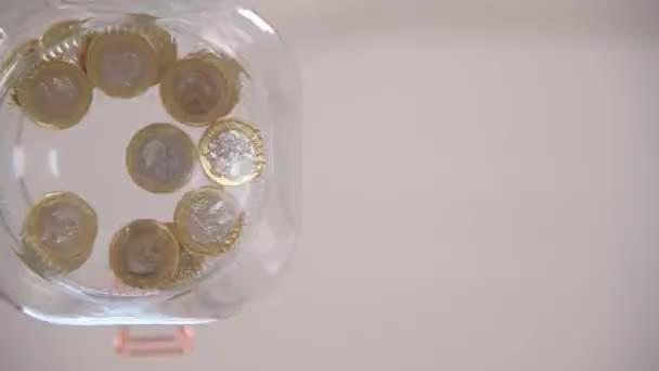 Worm Eye View Pound Coins Being Dropped Glass Jar — Stock Video