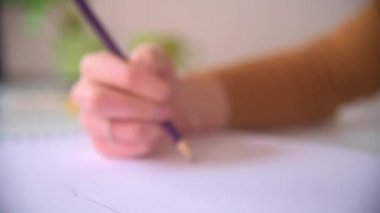 A close handheld tracking shot following a designer's hand as they create a design in a sketchbook