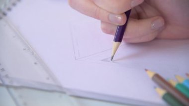A close up shot tracking over a designer creating a technical drawing in a sketchbook.