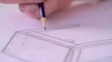 A close up handheld shot of a designer sketching in a notebook 