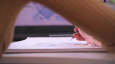 A track reveal shot showing a professional designer as they sketch out a design at a desk.