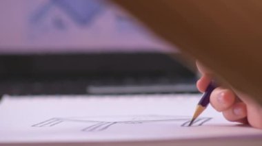 A slow-motion shot showing a woman sketching out technical designs at her desk