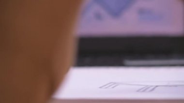 A slow-motion tracking shot revealing a woman sketching out a technical design at her desk