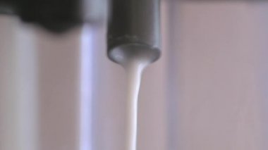 Yavaş çekimde, köpüklü sütün kahve makinesinden dağıtıldığı yakın çekim.