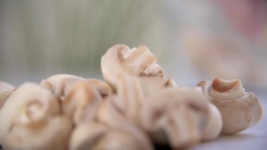 Ön planda odaklanmış bir mantar yığını, arka planda eller, hafifçe bulanık kesilmiş ve mantarları üst üste yığmış..