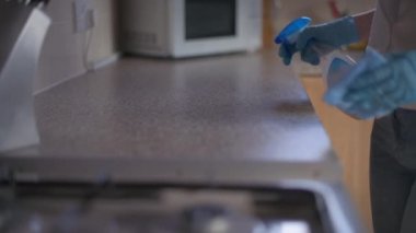 Mutfak tezgahlarını temizlemek için dezenfektan kullanan birinin yakın çekim görüntüsü.