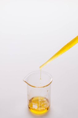 Plastik bir pipetten cam bir şişeye susam yağı döküyor.