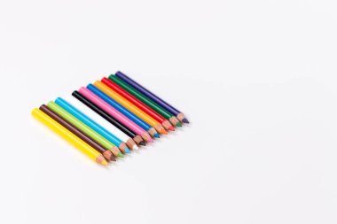 Beyaz arka planda keskin uçlu on iki küçük ve ince renkli kalem.