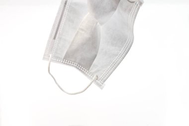 Tek kullanımlık koruyucu bir yüz maskesi. Beyaz bir arka planda beyaz iplikle burun ve ağzı kaplıyor.