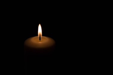 Siyah bir zemin üzerinde yanan turuncu-kırmızı bir mum alevi, sadece görünen bir mumun üst parçası.