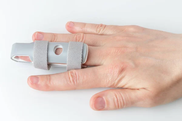 Grey plastic two-sided Finger Splint with two convenient hook-and-loop straps on an broken middle finger, holding a finger straight with orthopedic tool