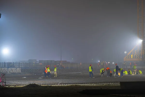 Workers on a night shift prepare a reinforcing cage for pouring it with concrete. Making the foundation.