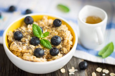 Yulaf lapası - yulaf gevreği yaban mersini ve nane yaprakları masa örtüsü ve ahşap arka plan