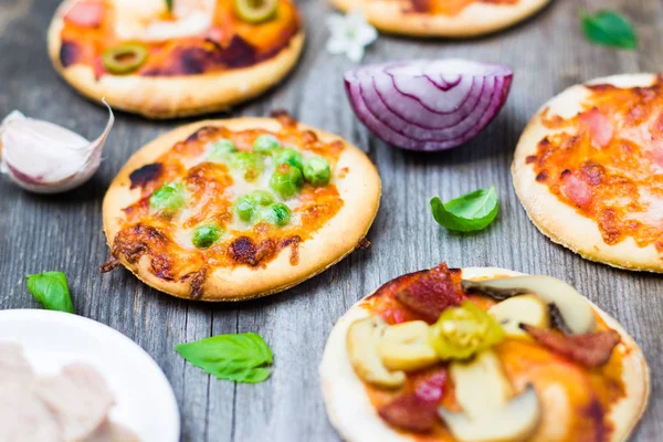 Küçük pizza ve malzemeler ahşap arka plan üzerinde