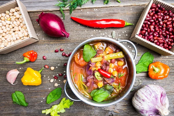 Fondo colorido de la comida. Sopa de verduras Bio con garbanzos y frijoles Adzuki en maceta con ingredientes de cocina en mesa de madera . — Foto de Stock