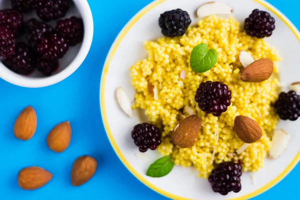 Üstten Görünüm püre darı tahıl böğürtlen ve mavi zemin üzerine badem.