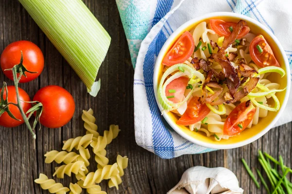 Kiraz domates, sarımsak ve pırasa ile ahşap arka plan üzerinde ham maddeler ile makarna