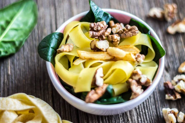 Ceviz ve taze ıspanak yaprakları üzerinde ahşap arka plan ile makarna.