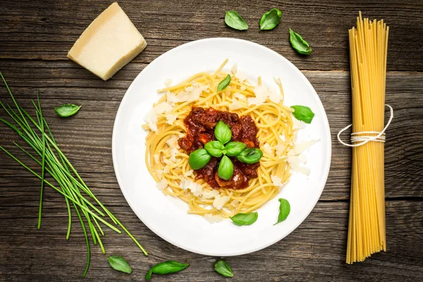 Espaguete com folhas de manjericão, queijo e molho de tomate em fundo de madeira Imagem De Stock